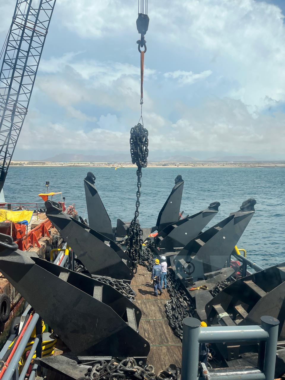 Crane lifting heavy anchor chains on a salvage barge deck