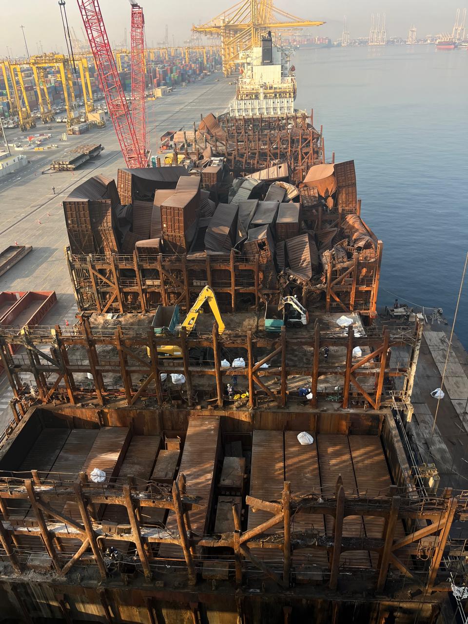 Fire-damaged cargo vessel under salvage at port