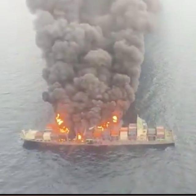 Container vessel on fire at sea with heavy smoke